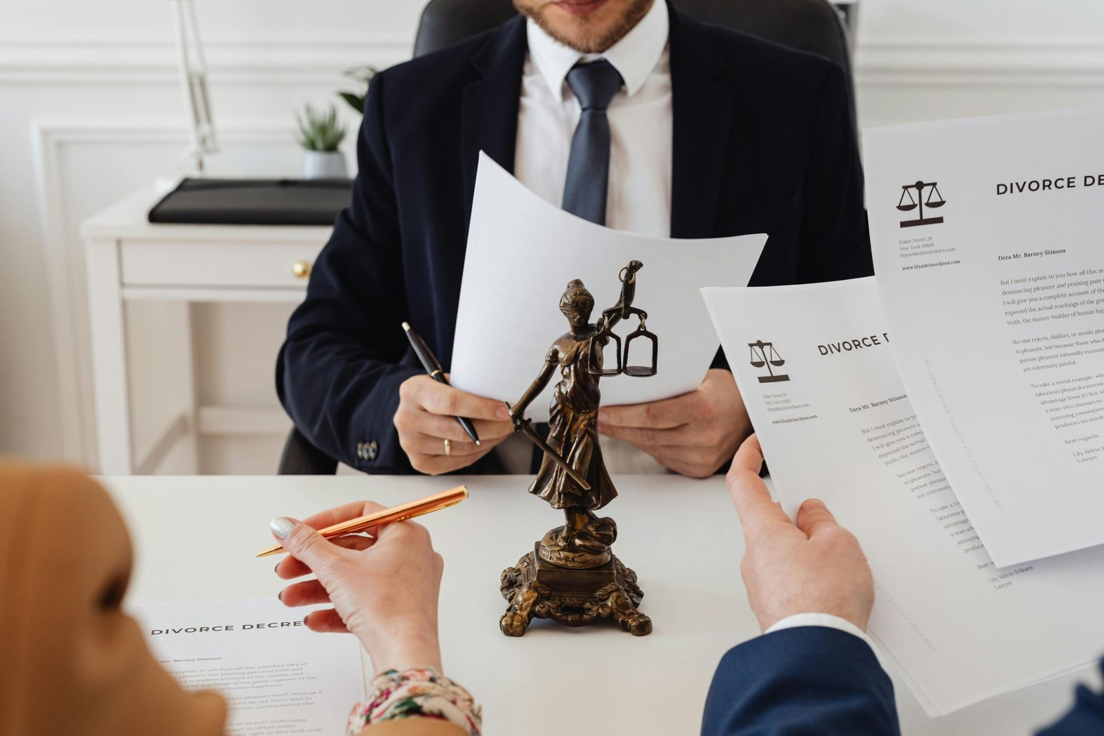 Moosavi & Abogados Legal professionals reviewing divorce documents in a law office with a Lady Justice statue.